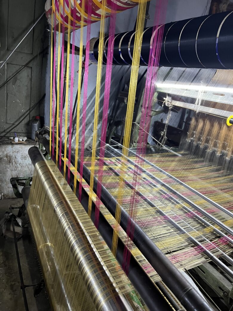 Montage des fils colorés sur un métier à tisser traditionnel avant le tissage d'une soie