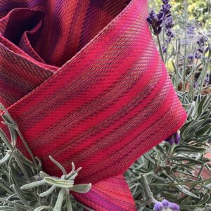 Twilly d'exception Tohora en soie de mûrier lourde 22 momme rouge rubis et violet posé sur un buisson de lavande